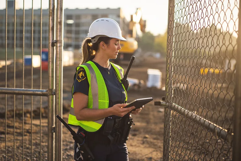 Security guard checking the gate of a construction site at sunrise