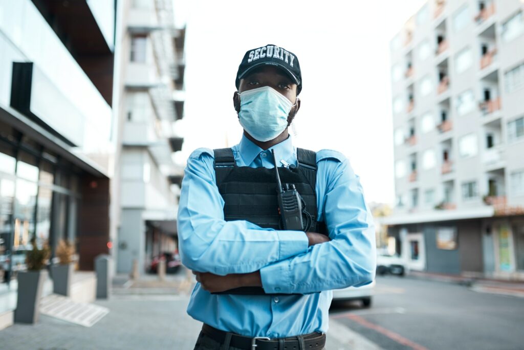 Portrait of a confident masked young security guard standing guard outdoors